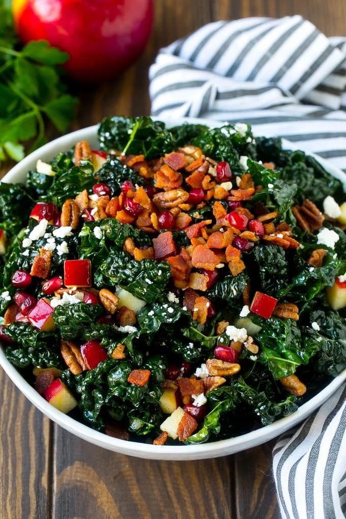 A bowl of tuscan kale salad garnished with cooked bacon.