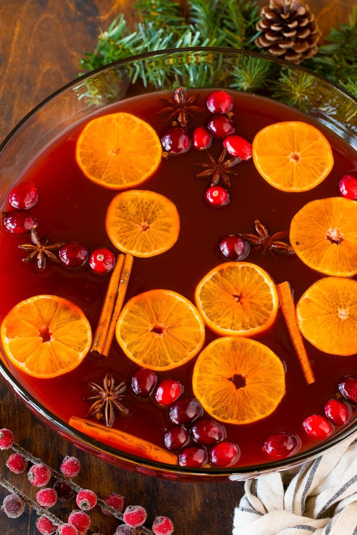 A bowl of Kinderpunsch garnished with orange slices, cinnamon sticks and cranberries.