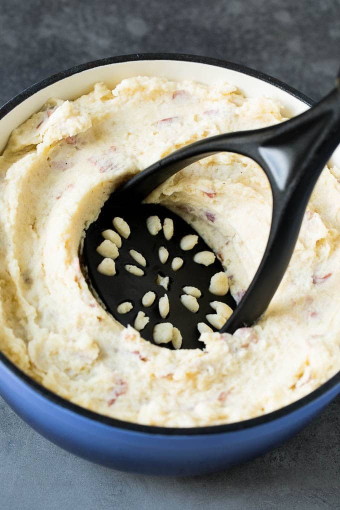 A potato masher in a pot of potatoes.