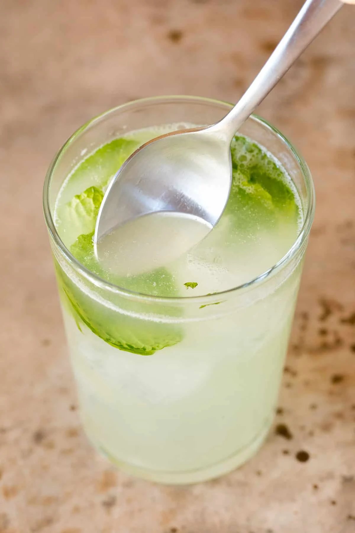 A spoon in a drink stirring it.