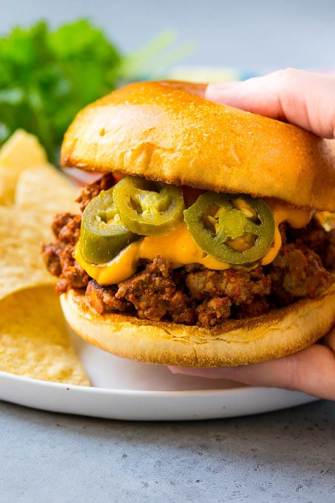 A nacho sloppy joe being held by a hand.