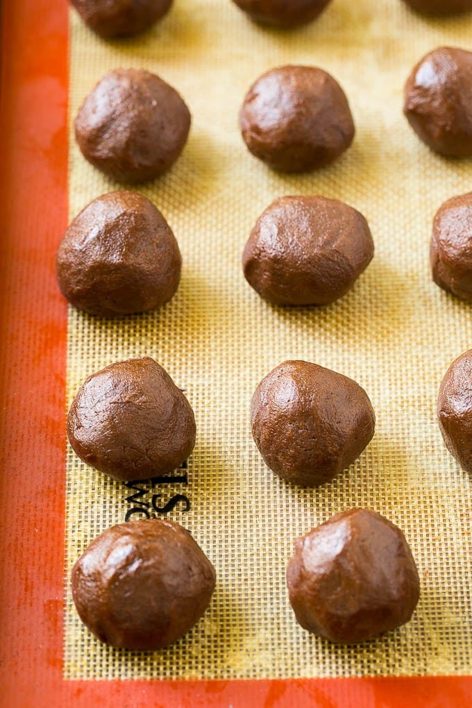 Balls of chocolate cookie dough on a baking sheet.