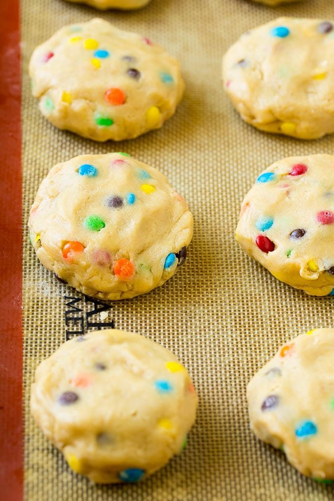 Cookie dough balls stuffed with Oreo cookies on a sheet pan.