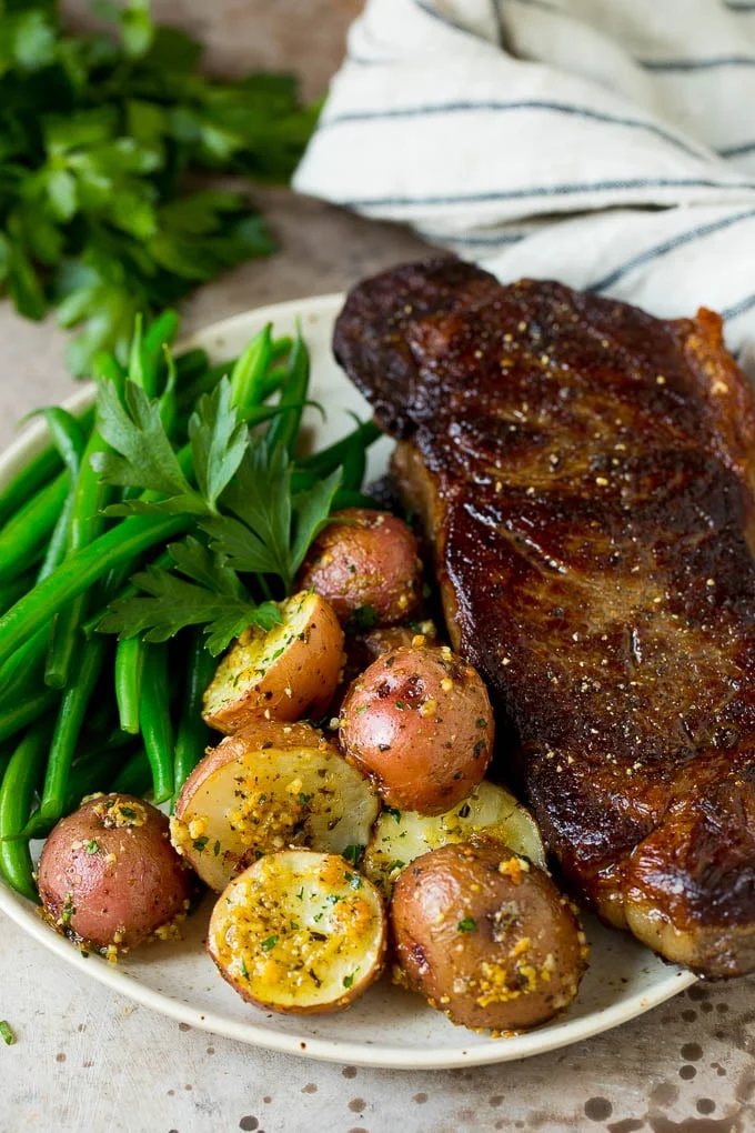 Oven roasted potatoes on a plate with steak and green beans.