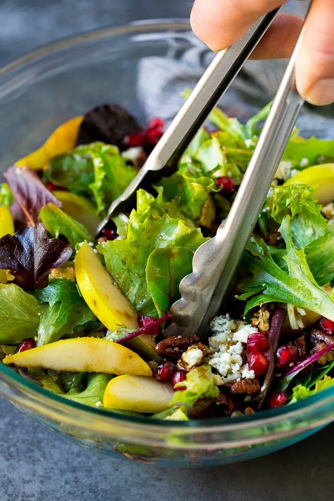 Tongs serving up a portion of pear salad.