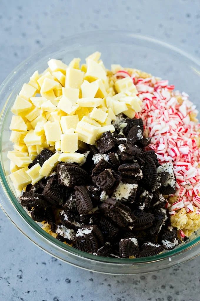 A bowl of dough with Oreo pieces, white chocolate chunks and crushed candy canes.