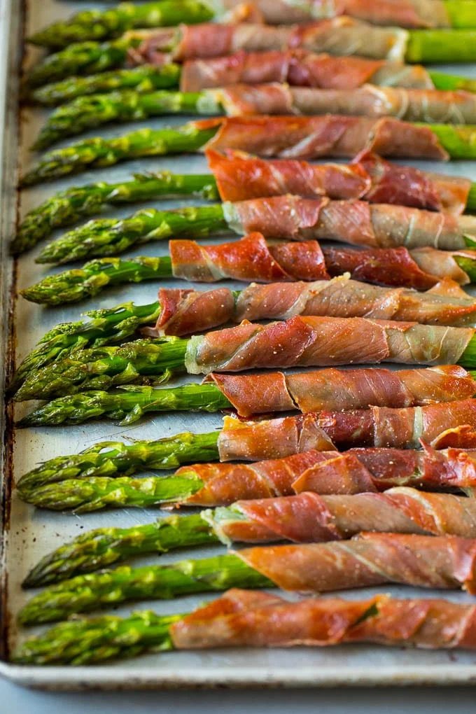 Prosciutto wrapped asparagus on a sheet pan.