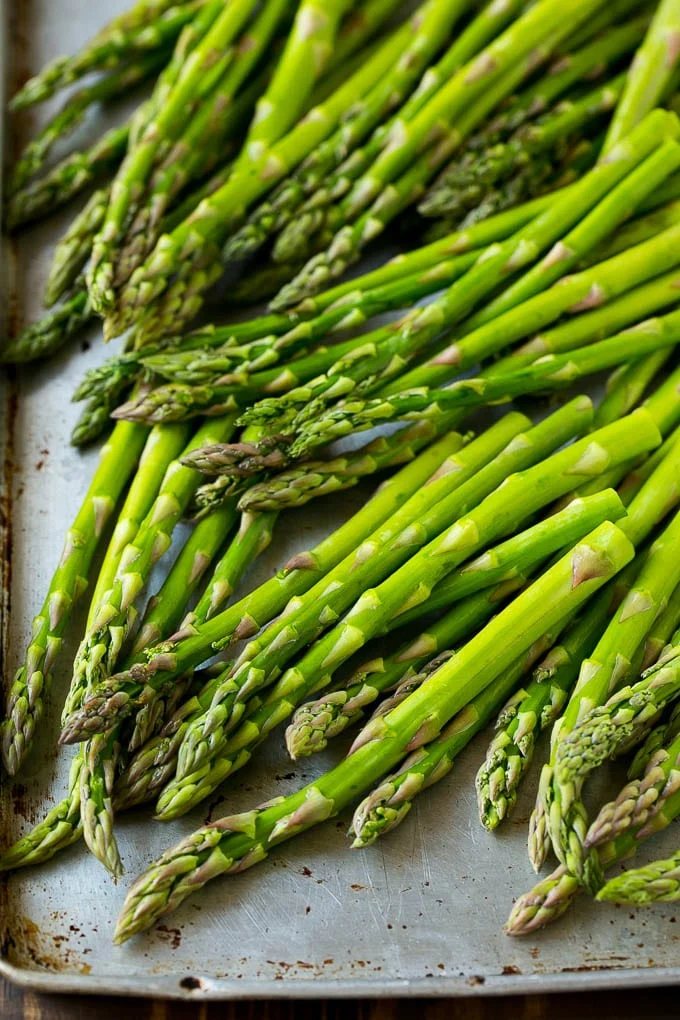 Raw asparagus spears on a sheet pan.