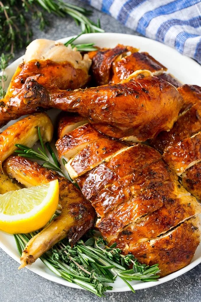 Carved roasted chicken on a serving platter with fresh herbs.