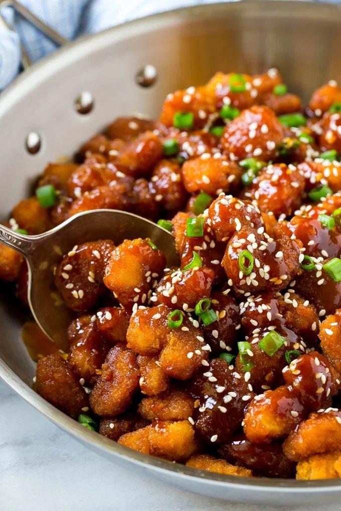 A pan of crunchy sesame shrimp tossed in an Asian style sauce.