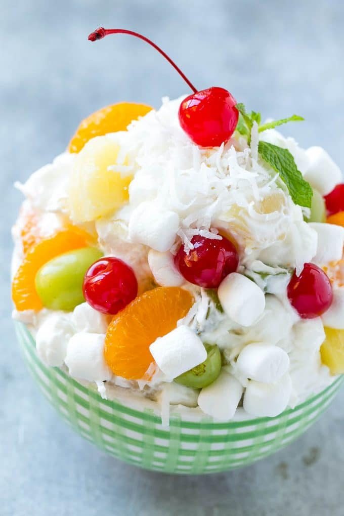 A bowl of ambrosia salad with a variety of colorful fruit with marshmallows and coconut, tossed in a light and silky dressing.