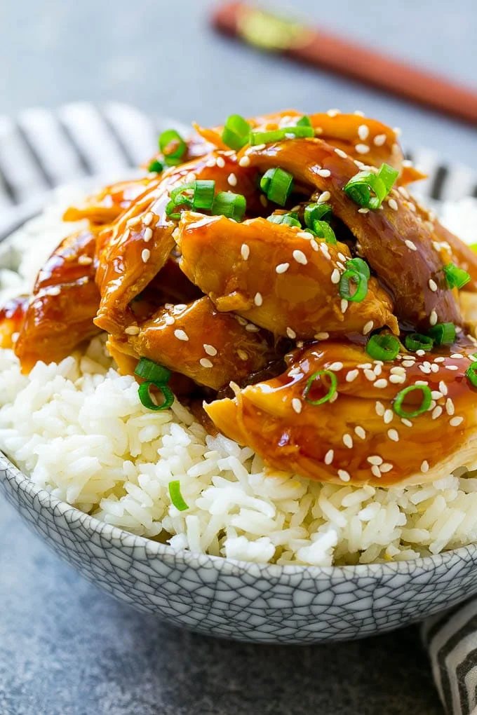 A bowl of rice topped with shredded crock pot teriyaki chicken.