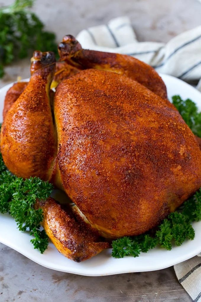 Smoked chicken on a serving platter garnished with parsley.