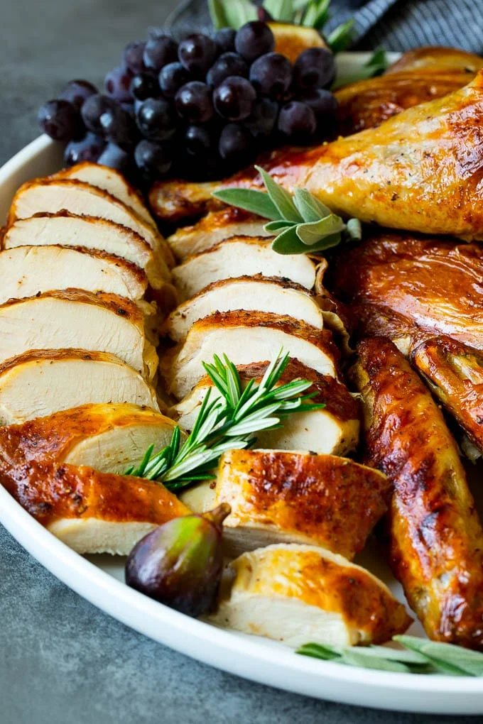 Sliced spatchcock turkey on a serving platter garnished with herbs.