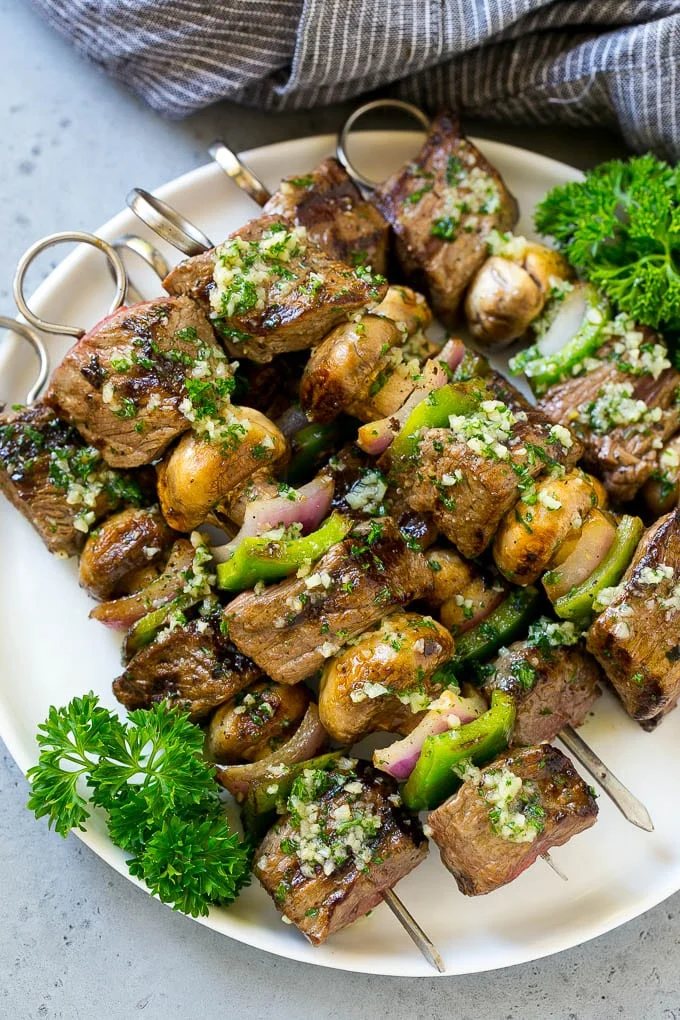 A plate of grilled steak kabobs with garlic butter.