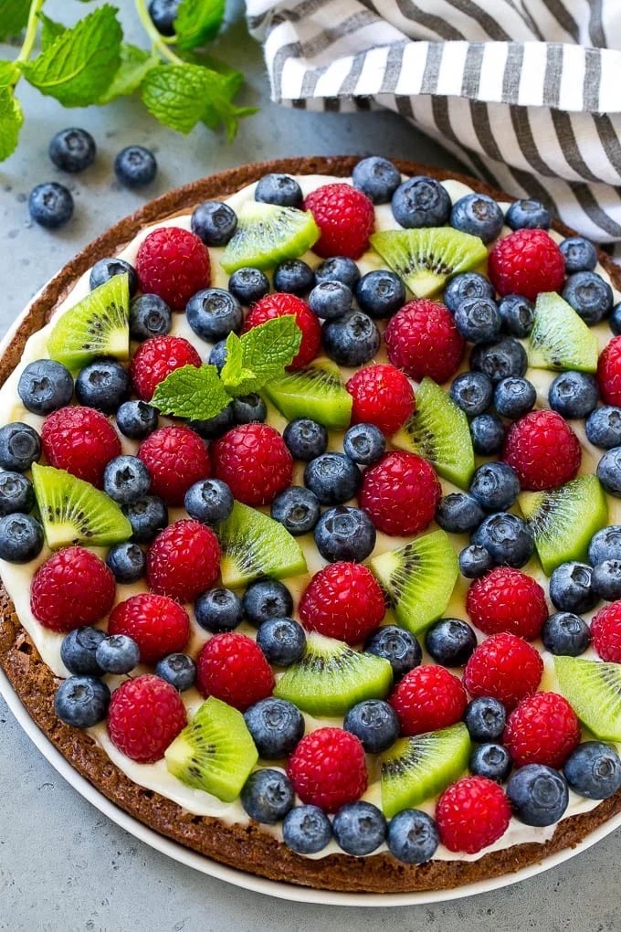 Brownie pizza topped with cream cheese frosting and fresh fruit.