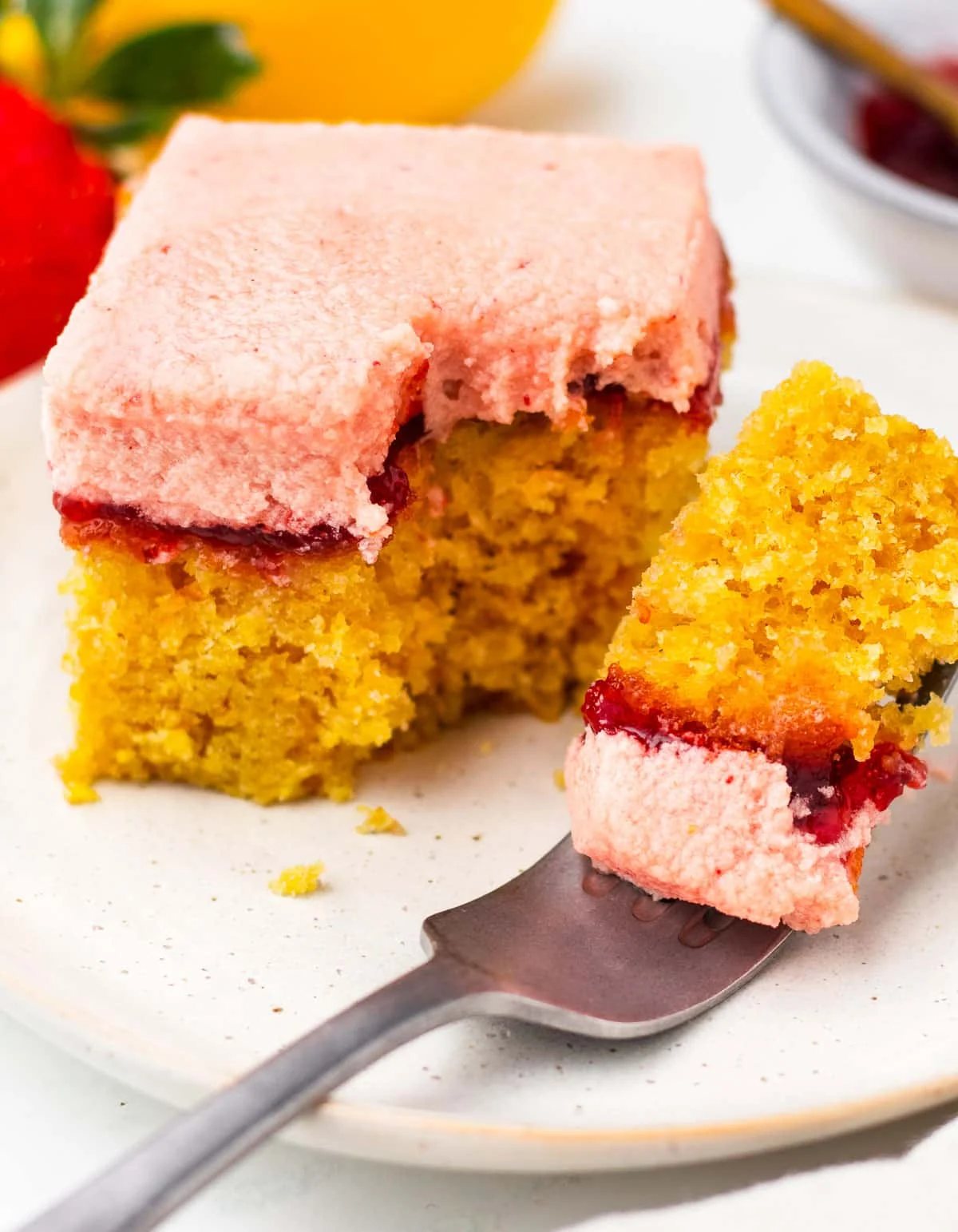 A slice of strawberry lemon cake with a fork cutting off a piece.