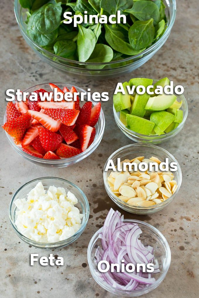 Bowls of ingredients like feta cheese, almonds, red onion and avocado.