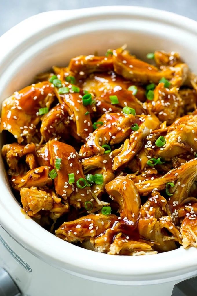Slow cooker teriyaki chicken with shredded chicken breasts, kitchen-made teriyaki sauce, sesame seeds and green onions.