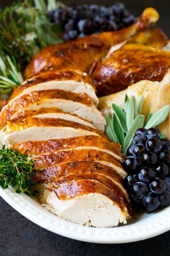 Sliced Thanksgiving turkey on a serving platter with fresh herbs.