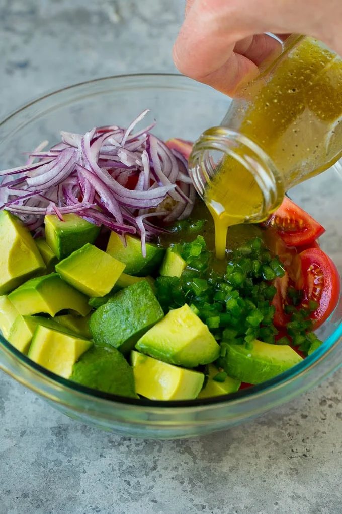 Dressing being poured over chopped veggies.