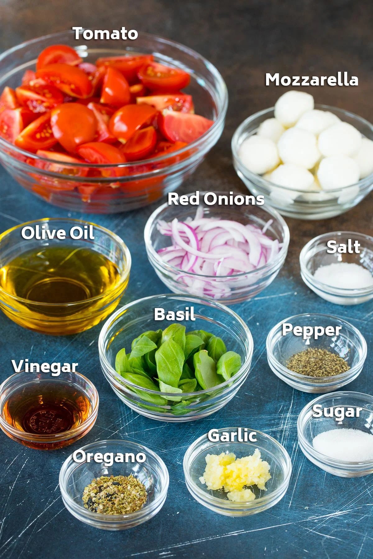 Bowls of ingredients including basil, cheese, onions, olive oil and seasonings.