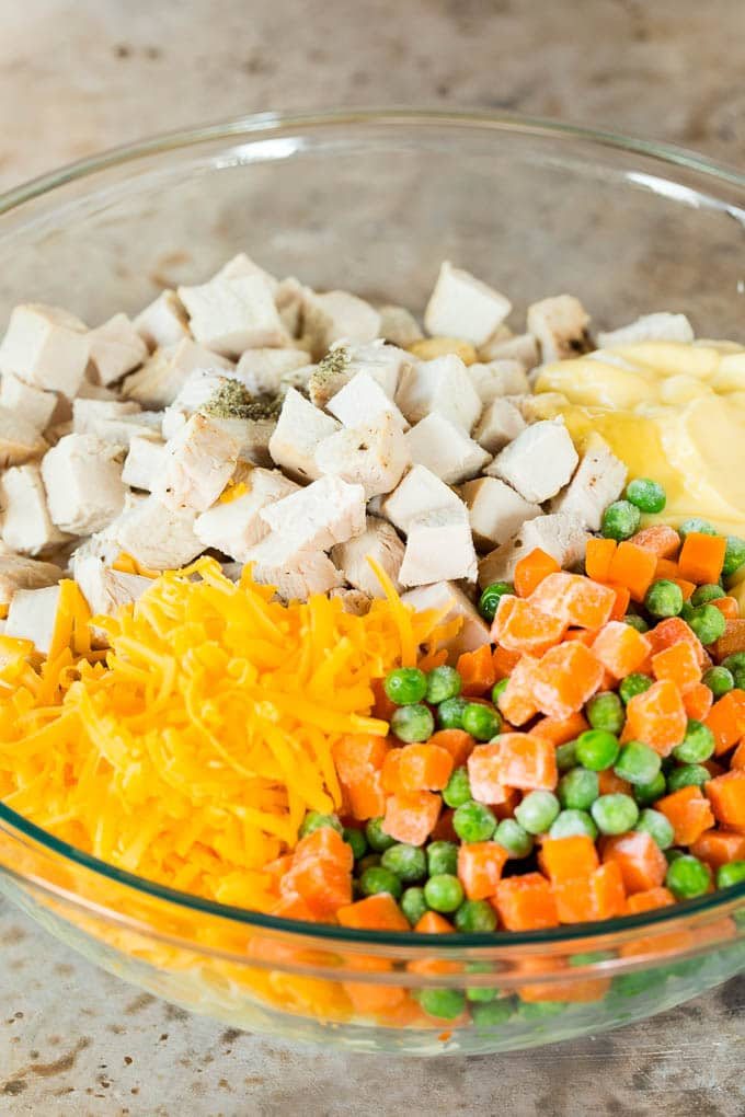 Meat, pasta, frozen vegetables and cheese in a large bowl.