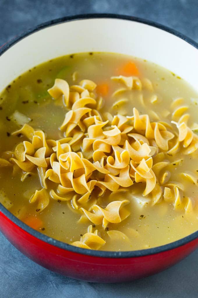 A pot of soup with egg noodles on top.
