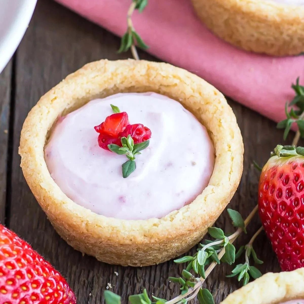 A picture of a cookie cup with a strawberry cheesecake filling.