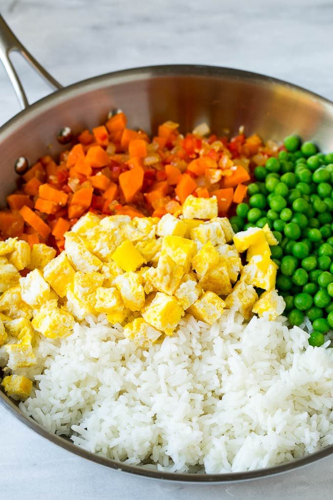Vegetables, scrambled egg, rice and peas in a frying pan.