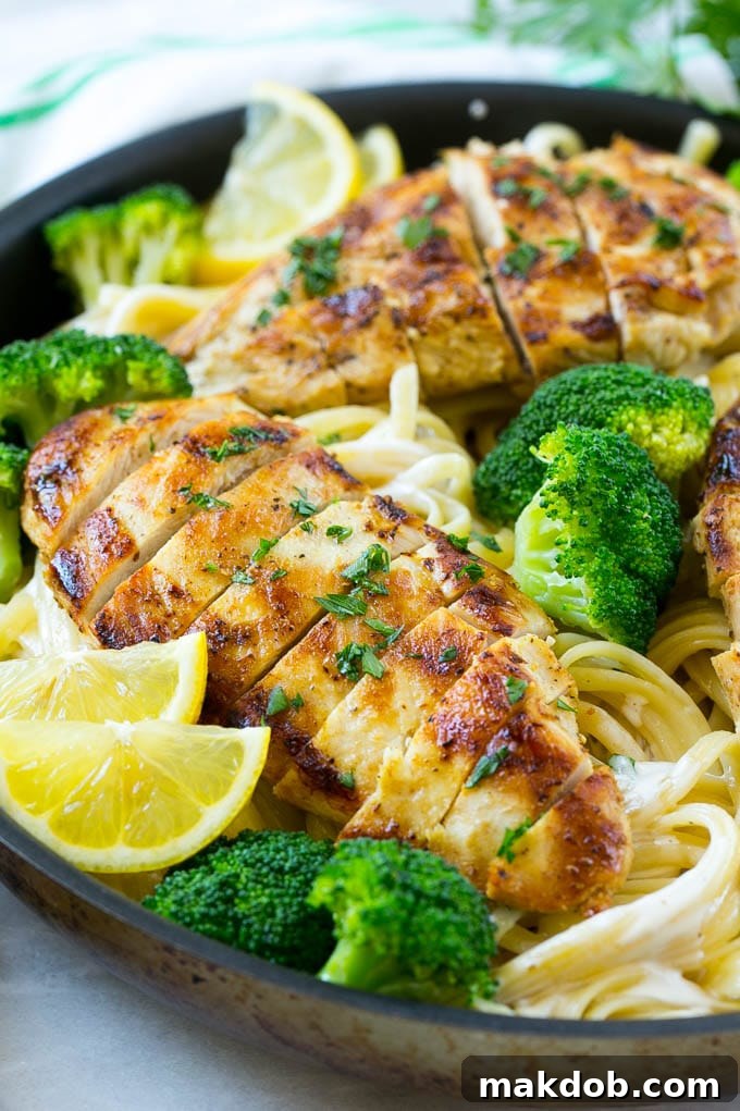 Sliced chicken breast with broccoli on top of creamy linguine pasta.