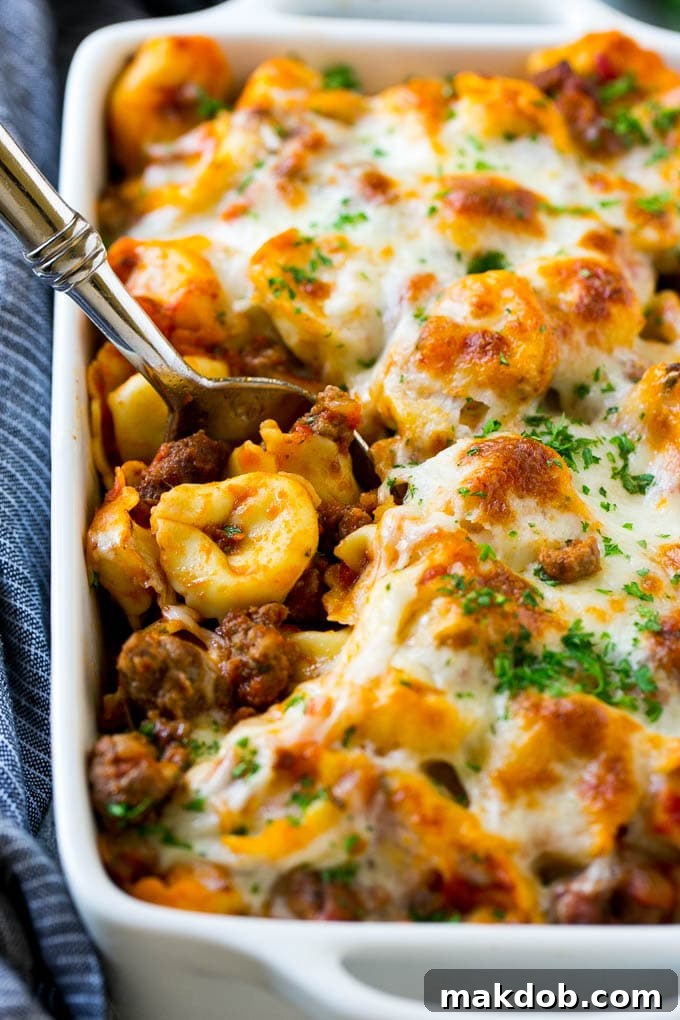 A pan of baked tortellini in a meat sauce, all covered with bubbly, melted cheese.