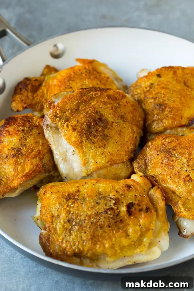 Seared golden-brown chicken thighs in a pan, ready for the slow cooker to make delicious apricot chicken.