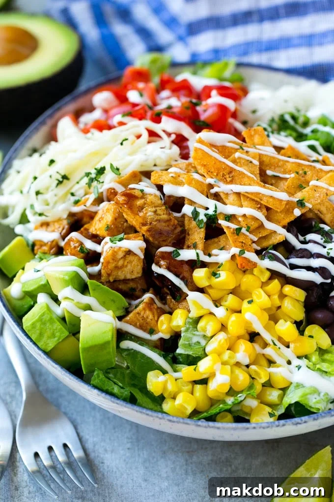 A vibrant bowl of BBQ chicken salad, artfully arranged and generously drizzled with creamy ranch dressing, inviting you to take a bite.