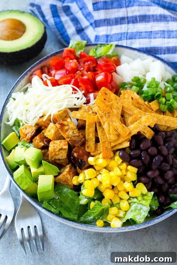 Healthy BBQ Chicken Salad with Fresh Ingredients A large bowl of fresh salad greens topped with generous portions of BBQ chicken, corn, black beans, avocado, diced tomatoes, and shredded cheese.
