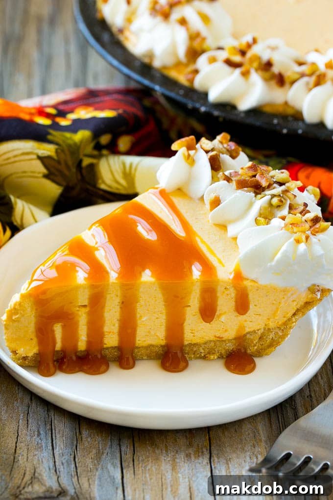 A slice of creamy no bake pumpkin cheesecake topped with a generous drizzle of caramel sauce and a few pecans.