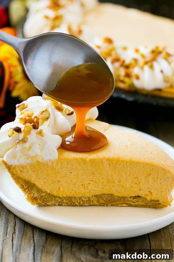 A spoon pouring rich caramel sauce over a freshly sliced piece of no bake pumpkin cheesecake.