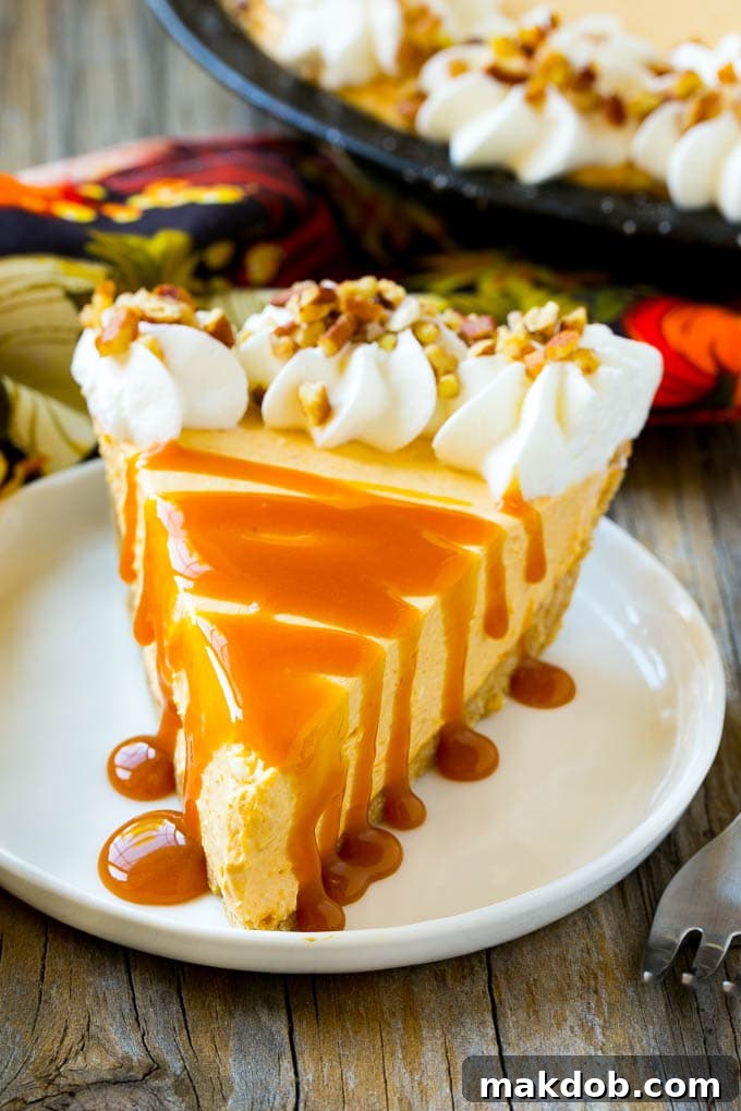 A slice of no bake pumpkin cheesecake topped with a caramel drizzle and small pieces of pecan.