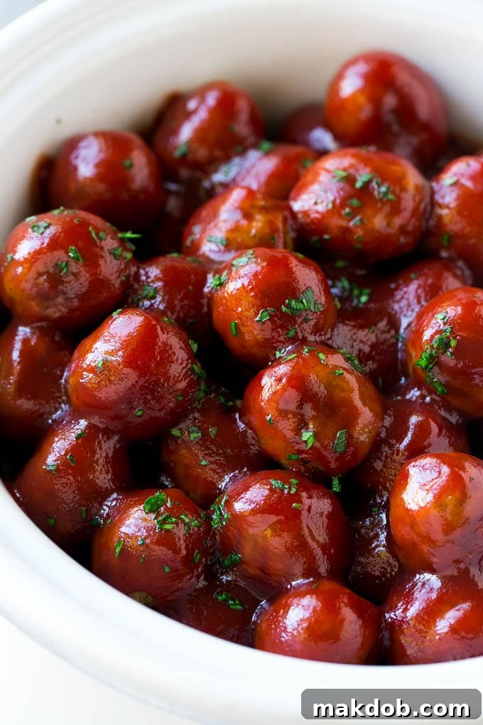 Cranberry meatballs simmering in a crock pot, topped with fresh parsley.