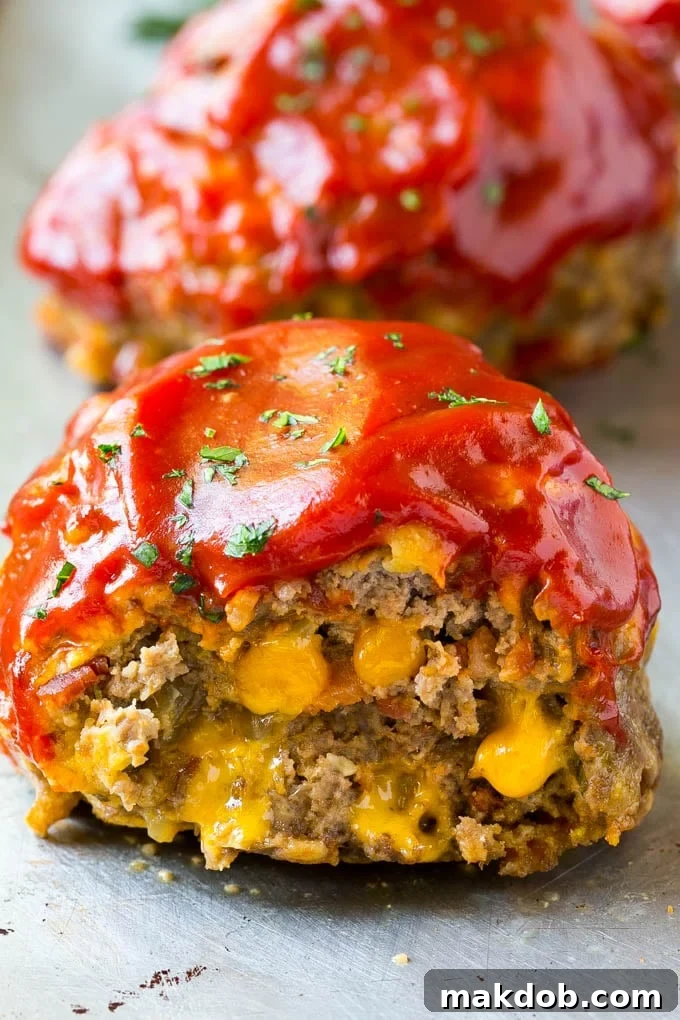Inside the Delicious Cheeseburger Meatloaf: Bacon and Cheddar Revealed A perfect cross-section of an individual cheeseburger meatloaf, showcasing the melted cheddar cheese and bits of savory bacon within.
