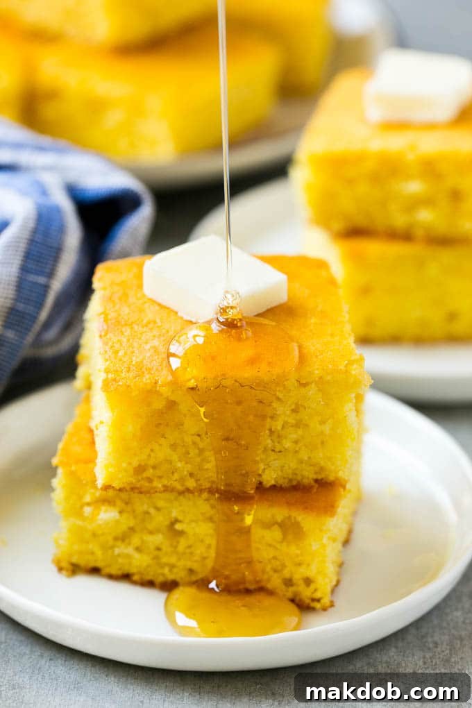 Best Honey Cornbread Recipe | Easy Buttermilk Cornbread | Homemade Cast Iron Cornbread A stack of golden honey cornbread squares topped with melting butter and a drizzle of golden honey, ready to be served as a delicious side dish.