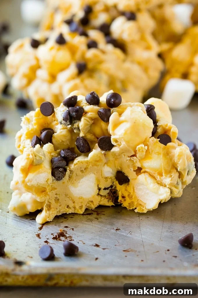 A close up of an avalanche cookie with a bite taken out of it, showcasing the layers of peanut butter, white chocolate, marshmallows, and crispy rice cereal.