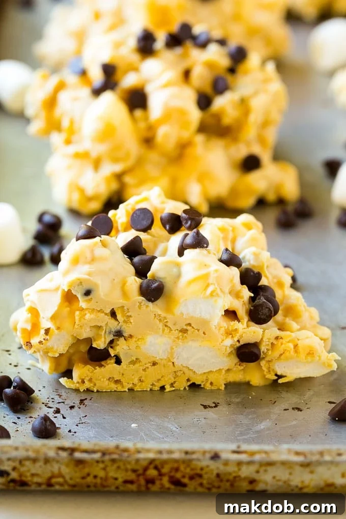 A cross section view of a no bake cookie, showing the distinct layers of white chocolate, peanut butter, rice krispies, and mini marshmallows.