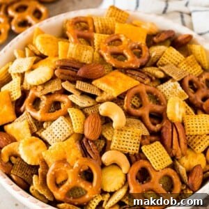 A large white serving bowl filled with savory homemade Chex mix, ready for snacking.