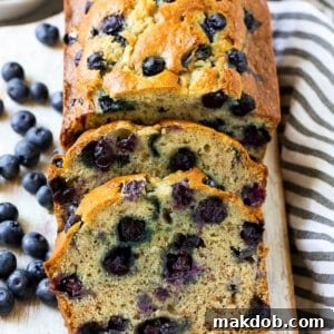 A freshly baked loaf of sliced blueberry banana bread, showcasing its moist texture and juicy blueberries.