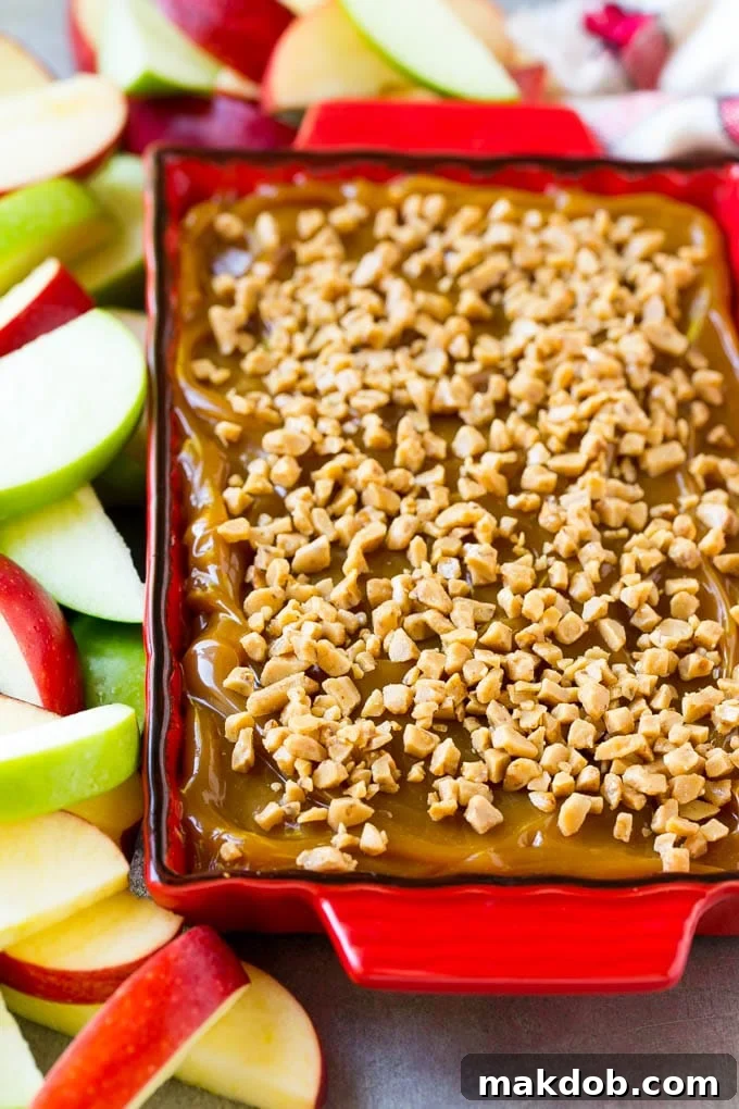Caramel apple dip generously topped with crunchy toffee bits, presented in a serving dish.