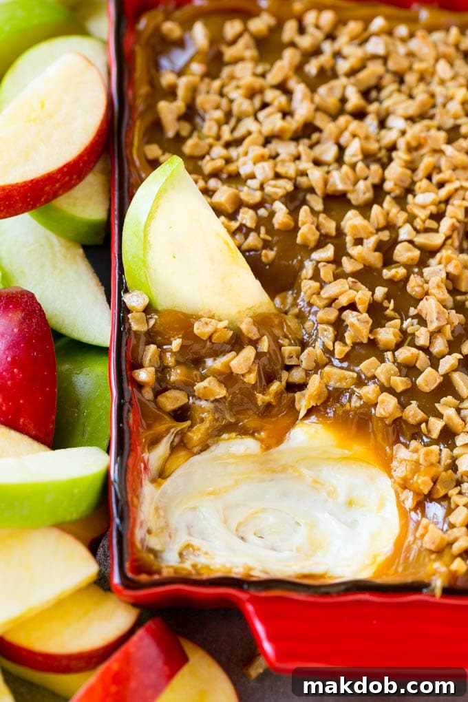 A crisp red apple slice submerged in the creamy, rich caramel apple dip.