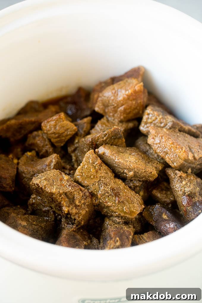 Slow Cooker Barbacoa | Beef Tacos | Crock Pot Beef Tacos #beef #tacos #crockpot #slowcooker #dinner #avocado #dinneratthezoo Cooked barbacoa cubes in a slow cooker, showcasing their tenderness.