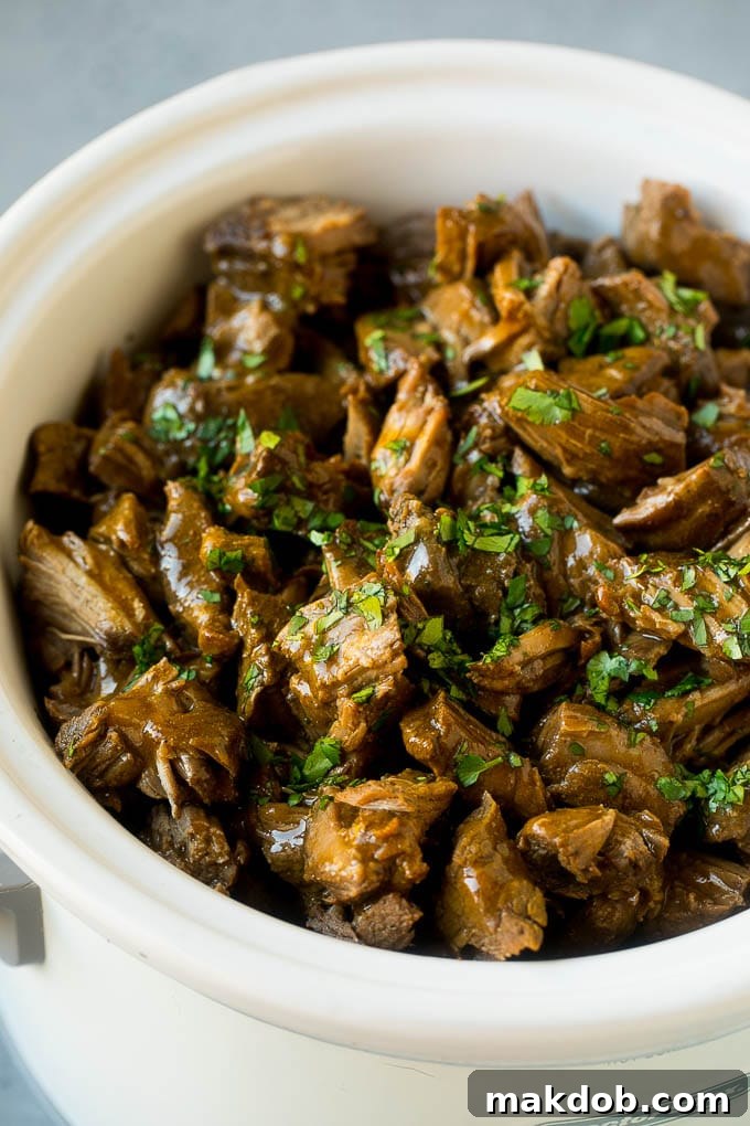 Slow Cooker Barbacoa | Beef Tacos | Crock Pot Beef Tacos #beef #tacos #crockpot #slowcooker #dinner #avocado #dinneratthezoo Shredded barbacoa beef in a slow cooker, topped with fresh cilantro.