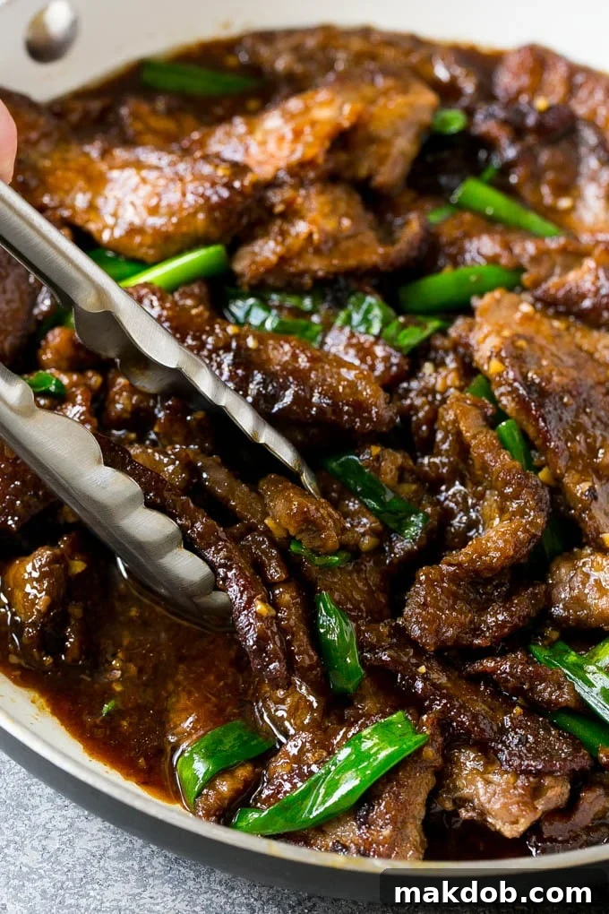 Mongolian Beef Recipe | Asian Beef Recipe | Chinese Beef | Beef Stir Fry #Chinese #Mongolian #Asian #mongolianbeef #beef #dinneratthezoo #dinner A pan of homemade Mongolian beef with serving tongs, garnished with fresh green onions.